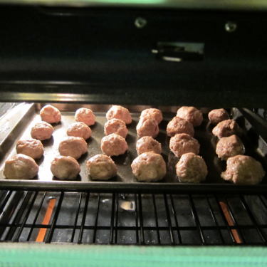 Meatballs cooking in a pan in the oven.