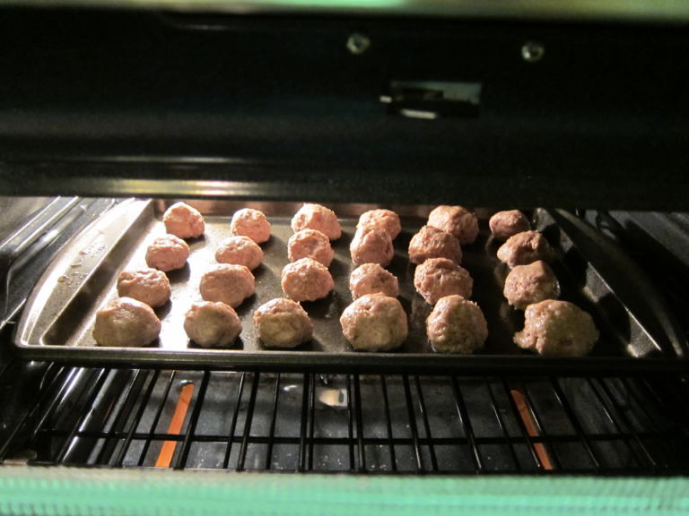 Meatballs cooking in a pan in the oven.